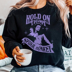 May include: Black sweatshirt with a purple graphic design that says "Hold On Tight Spider Monkey" with a cartoon image of a woman holding a spider.