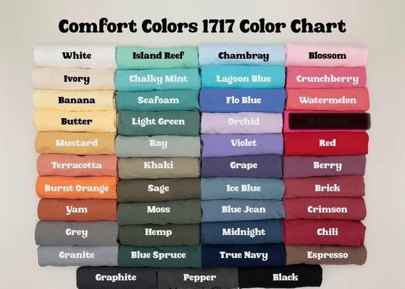May include: Color chart of Comfort Colors 1717, featuring a variety of fabric colors. The chart displays a range of hues, including white, blue, pink, green, and brown. Each color is labeled with its name, such as "Chambray" and "Blossom".