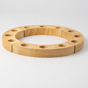 Könnte beinhalten: Ein Kerzenring aus Holz mit 10 gleichmäßig verteilten Kerzenhaltern. Der Ring ist aus hellem braunem Holz gefertigt und in Abschnitten zusammengesetzt.