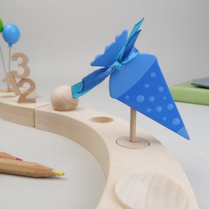 Könnte beinhalten: Ein Holz-Adventskalender mit einem blauen und weißen kegelförmigen Ornament, einer Holz-Kugel und den Zahlen 1, 2 und 3.