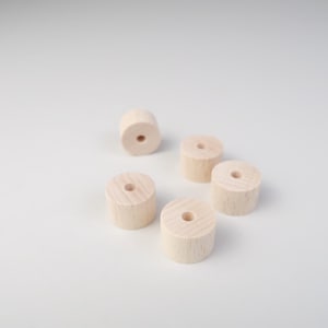 Könnte beinhalten: Fünf unfertige Holzringe mit einem Loch in der Mitte. Die Ringe sind in einem Halbkreis auf einer weißen Oberfläche angeordnet.