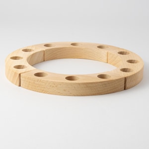 Könnte beinhalten: Ein Kerzenring aus Holz mit zehn Kerzenhaltern. Der Ring ist aus Naturholz gefertigt und eignet sich perfekt für eine Geburtstagsfeier oder einen anderen besonderen Anlass.
