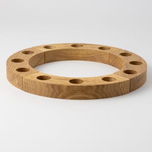 Könnte beinhalten: Ein Adventskerzenhalter aus Holz mit 12 einzelnen Steckplätzen für Kerzen. Der Halter ist aus Naturholz gefertigt und hat eine runde Form.