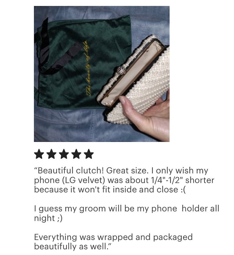 Peut inclure: Une pochette de soir&eacute;e blanche en perles avec une fermeture dor&eacute;e et un petit bijou en perle. La pochette est ouverte et l'int&eacute;rieur est doubl&eacute; d'un tissu beige clair. La pochette est pos&eacute;e sur un sac en velours vert avec les mots "The beauty of life" brod&eacute;s en fil d'or.