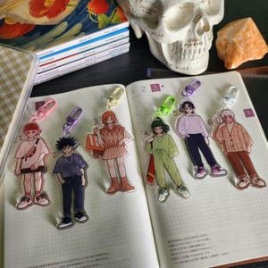 May include: Six acrylic keychains featuring anime-style characters, each with a colored lobster clasp. The characters are numbered one through six and display various outfits including sweaters, pants, and skirts, with some carrying bags or accessories.