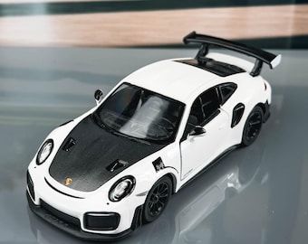 May include: A white and black toy sports car with a rear spoiler. The car has black wheels and a black bonnet. The car is on a reflective surface.