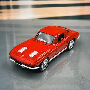 May include: A vibrant red toy car with silver wheels and trim. The classic sports car model has a sleek design with a low profile, visible vents on the hood, and a detailed interior. The car is a miniature replica, likely a collectible item.
