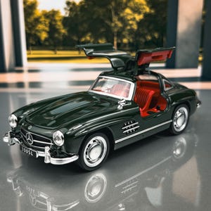 Op de afbeelding: Een donkergroene Mercedes-Benz 300SL modelauto met vleugeldeuren open, met een rood interieur. De auto heeft zilveren accenten en staat tegen een vage achtergrond van bomen en een gebouw.