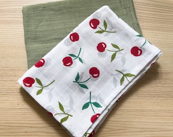 May include: Two kitchen towels, one green and one white with a red cherry pattern.