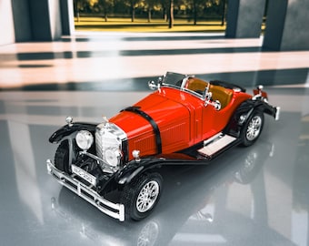 Op de afbeelding: Een rode vintage speelgoedauto met zwarte spatborden en zilveren wielen. De auto heeft een beige interieur en een zwarte riem over de motorkap. De voorkant van de auto heeft een zilveren grille en de nummerplaat luidt "IIC-2013".