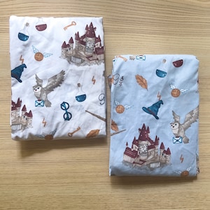May include: Two blue and white twin-sized bed sheets with a Harry Potter theme. The sheets feature a Hogwarts castle, owls, and other Harry Potter symbols. The text "9 3/4" is printed on one sheet.