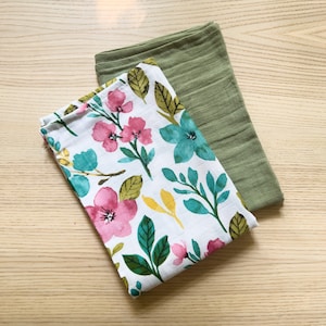 May include: Two fabric cloths, one with a floral pattern in pink, green, and blue on a white background, and the other a solid green color.