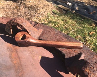 May include: A wooden smoking pipe with a dark brown stain and a natural wood grain pattern. The pipe has a rounded bowl and a long, curved stem.