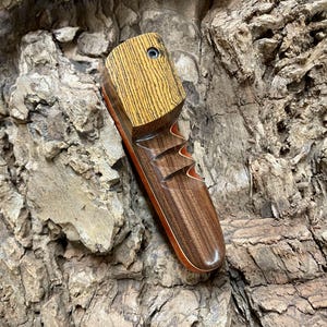 Puede incluir: Una taza de cerámica blanca con un asa negra y el texto "But First, Coffee" en negrita negra. La taza se encuentra sobre un fondo borroso, sugiriendo un ambiente acogedor.