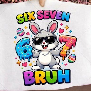 Puede incluir: Camiseta gráfica blanca con un conejito de dibujos animados con gafas de sol, sosteniendo un donut con el número 6 y un donut con el número 7. El texto "SIX SEVEN BRUH" se muestra en letras coloridas, con huevos de Pascua y estrellas.