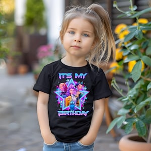 May include: A black t-shirt featuring a colorful graphic design with the text "IT'S MY BIRTHDAY". The design includes a star shape with three cartoon characters. The text and star have a neon-style effect.