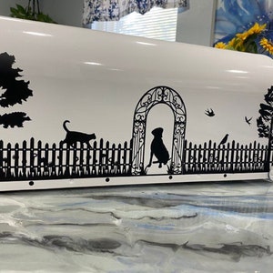 May include: White mailbox with a black silhouette design of a dog, cat, birds, and a fence with a gate. The design also includes a tree and a bush.
