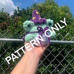 Może przedstawiać: Zielona i fioletowa dziana żaba w fioletowym i żółtym kapeluszu w kształcie gwiazdy. Żaba trzyma fioletową wstążkę w pysku. Na obrazie nałożony jest tekst "PATTERN ONLY".