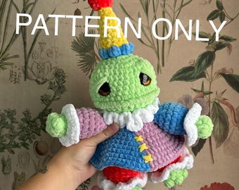May include: A handmade crochet doll in the shape of a whimsical character. The doll is primarily green, with a yellow and blue hat, a pink and blue outfit, and red accents. The text "PATTERN ONLY" is displayed across the top.