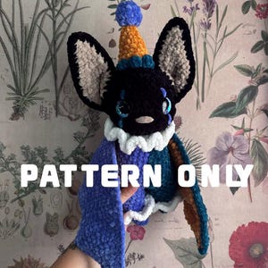Può includere: Un pipistrello di peluche all'uncinetto con testa nera, grandi orecchie e ali blu e marroni. Indossa un cappellino da festa giallo e blu e un colletto bianco a balze. Il testo PATTERN ONLY è sovrapposto in bianco al centro dell'immagine.