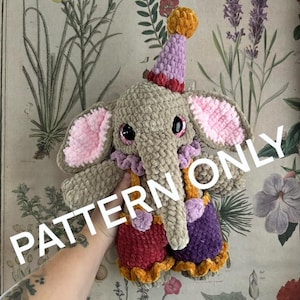 May include: A crocheted elephant toy in shades of grey, pink, purple, red, and orange. The elephant wears a party hat and a ruffled collar. The text "PATTERN ONLY" is visible on the image.