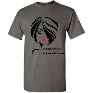 May include: A dark gray t-shirt with a black and white silhouette of a woman with red lips. The text "Be Great On Purpose" and "Be Great With Purpose" is printed below the silhouette.