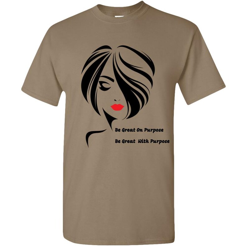 May include: A tan t-shirt with a black and white silhouette of a woman with red lips. The text "Be Great On Purpose" and "Be Great With Purpose" is printed below the silhouette.