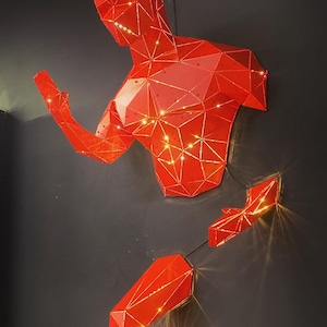 May include: A red, geometric, three-dimensional sculpture of a person in a running pose. The sculpture is made of many small, triangular pieces that are lit from within, creating a glowing effect.