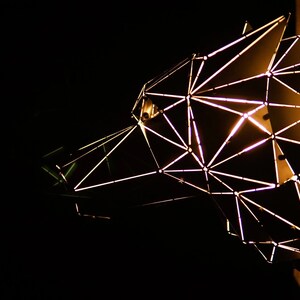 May include: A geometric metal sculpture of a bear's head with a light inside, illuminating the intricate design.