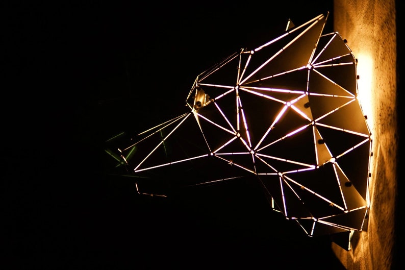 May include: A geometric metal sculpture of a bear's head with a light inside, illuminating the intricate design.
