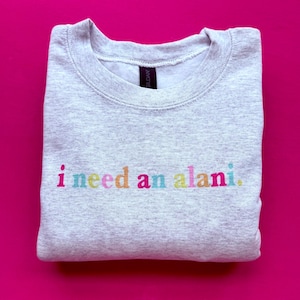 May include: A gray sweatshirt with the text "i need an alani." printed in rainbow colors.