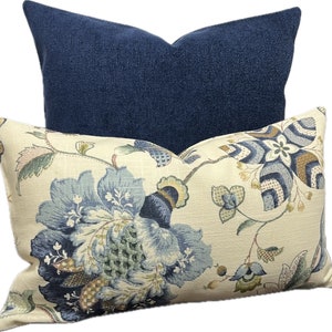 Puede incluir: Dos almohadas decorativas, una con un patr&oacute;n floral azul y la otra de color azul oscuro s&oacute;lido.