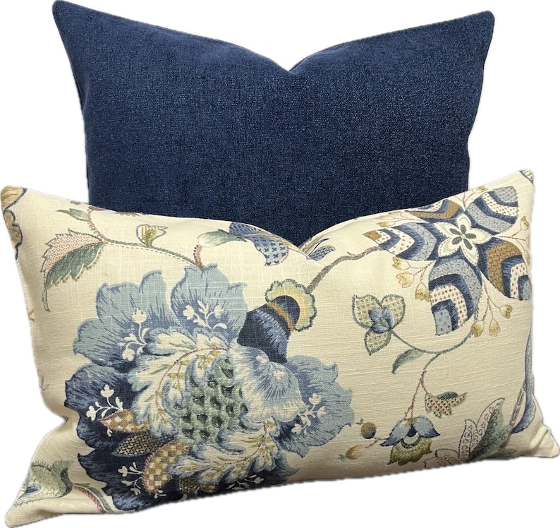 Puede incluir: Dos almohadas decorativas, una con un patr&oacute;n floral azul y la otra de color azul oscuro s&oacute;lido.
