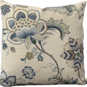 Puede incluir: Una almohada decorativa con un patr&oacute;n floral en tonos azules, verdes y marrones sobre un fondo crema.