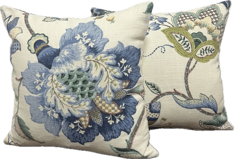 Puede incluir: Dos almohadas decorativas con un patr&oacute;n floral. Las almohadas son de color crema con dise&ntilde;os florales azules, verdes y marrones.