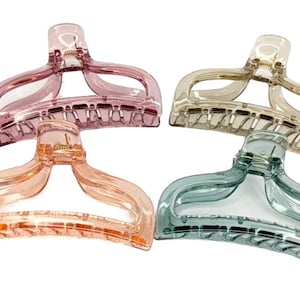 Puede incluir: Cuatro pinzas para el pelo translúcidas en tonos rosa, melocotón, beige y turquesa. Cada pinza tiene un asa curvada y una sección dentada para sujetar el cabello. Las pinzas están hechas de plástico transparente y brillante.