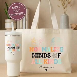 May include: A cream-colored canvas tote bag and a matching cream-colored insulated tumbler. Both items feature a colorful graphic of potted plants, a brain icon, and the text "NORMALIZE MINDS OF ALL KINDS" followed by the name "Jessica" and a heart.