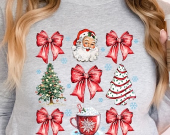 May include: A grey long-sleeved sweatshirt with a Christmas-themed design featuring Santa Claus, Christmas trees, red bows, and a cup of hot chocolate.