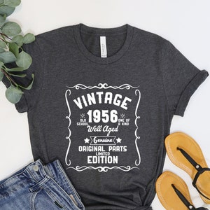 Może przedstawiać: Szary t-shirt z białym nadrukiem w stylu vintage, na którym widnieje napis "Vintage 1956" oraz tekst "Old School, Well Aged, One of a Kind, Genuine, Original Parts, Limited Edition".