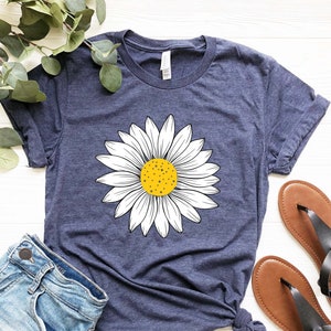 May include: A navy blue t-shirt with a white daisy graphic. The daisy has a yellow center.