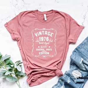 May include: A pink t-shirt with a white vintage style graphic that says "Vintage 1976 Old School Well Aged Genuine Original Parts Limited Edition".