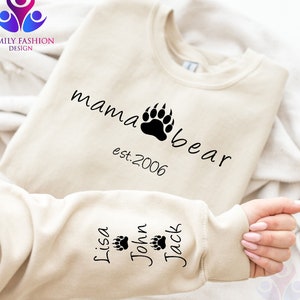 May include: A beige sweatshirt with the text "mama bear est. 2006" on the front and the names "Lisa", "John", and "Jack" with paw prints on the sleeve.