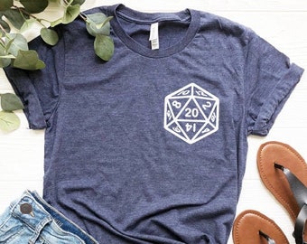 May include: A navy blue t-shirt with a white graphic of a twenty-sided die. The die has numbers 1, 4, 6, 8, 12, 14, 16, 18, 20 on its faces.