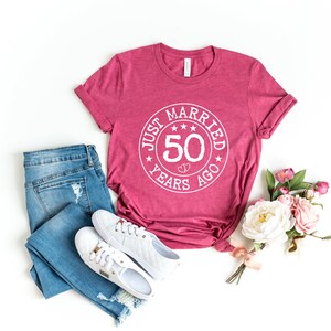 May include: A maroon t-shirt with a white circle graphic that says "Just Married 50 Years Ago" with stars around the circle.