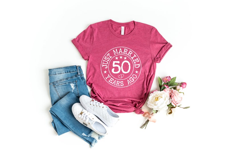 May include: A maroon t-shirt with a white circle graphic that says "Just Married 50 Years Ago" with stars around the circle.