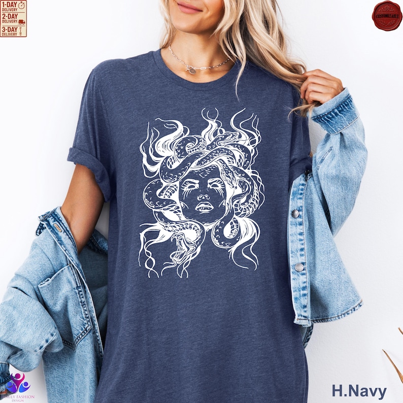 Pode incluir: Camiseta azul marinho com um gr&aacute;fico branco do rosto de Medusa e cobras. A camiseta tem mangas curtas e gola redonda. O texto "H.Navy" &eacute; vis&iacute;vel no canto inferior direito.