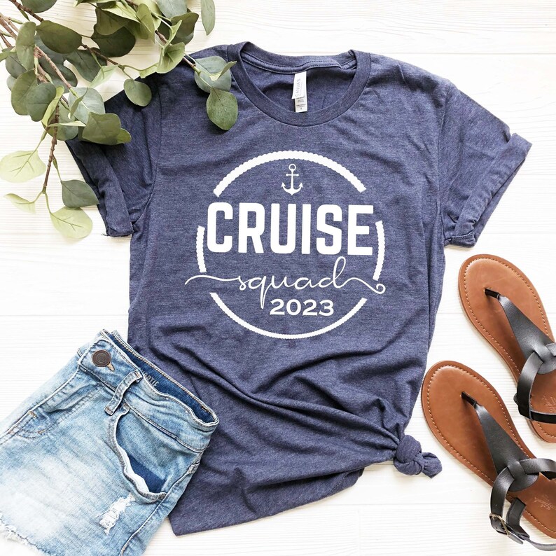 May include: A navy blue t-shirt with a white circle design that says "Cruise squad 2023" with an anchor symbol inside the circle.