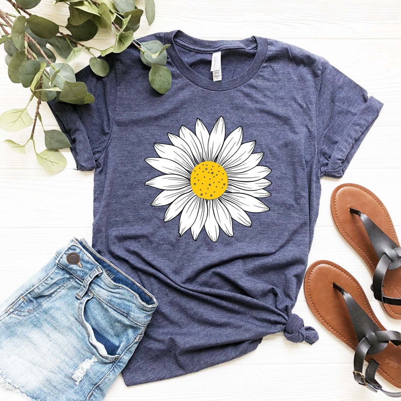May include: A navy blue t-shirt with a white daisy graphic. The daisy has a yellow center.