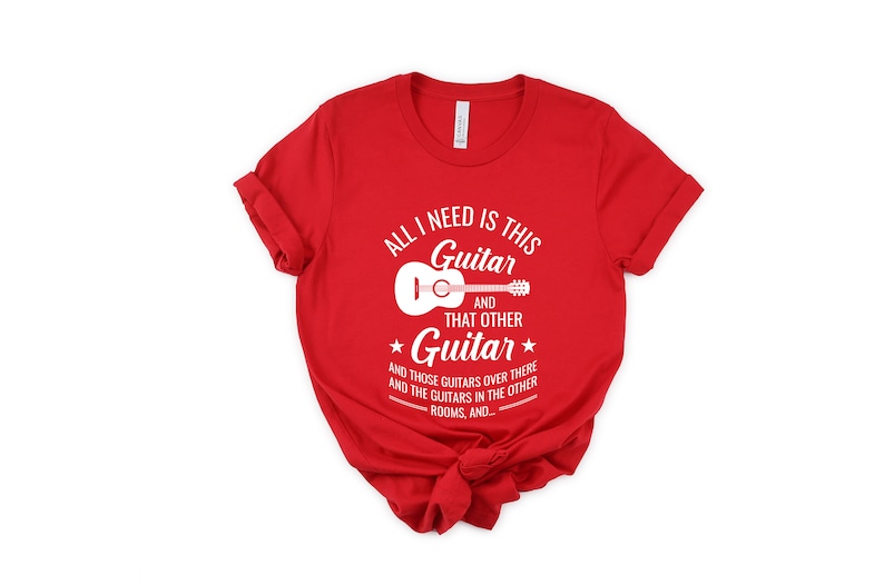 Puede incluir: Camiseta roja con un gr&aacute;fico blanco que dice "Todo lo que necesito es esta guitarra y esa otra guitarra y esas guitarras de all&aacute; y las guitarras en las otras habitaciones, y..."
