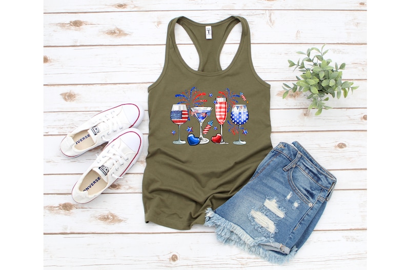 Pode incluir: Uma camiseta sem mangas verde com um gr&aacute;fico de quatro copos de vinho decorados com cores vermelho, branco e azul, que lembram a bandeira portuguesa. Os copos s&atilde;o cercados por fogos de artif&iacute;cio vermelho, branco e azul.